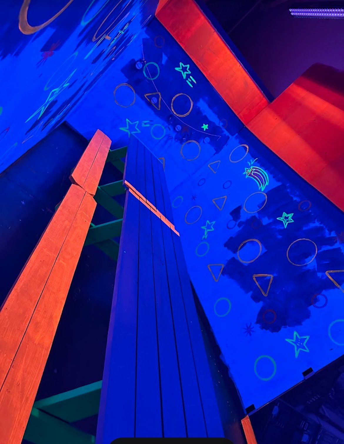 Neon-lit modern building facade with bright LED lights and cosmic symbols at Planet X Mini Glow Golf